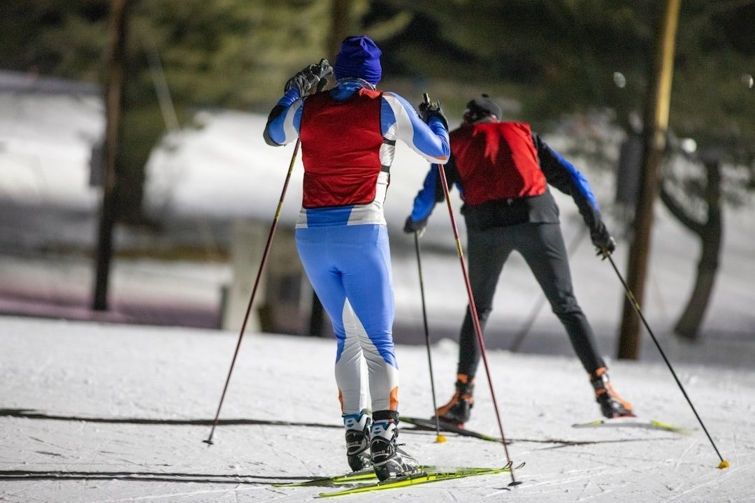 Kaksi hiihtäjää etenee lumisella ladulla pitopohjasuksilla